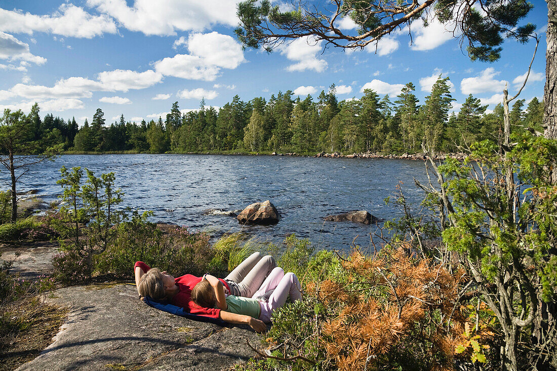 Mutter und Tochter liegen auf einem Felsen am Store Hindsjön, Kalmar Län, Smaland, Schweden