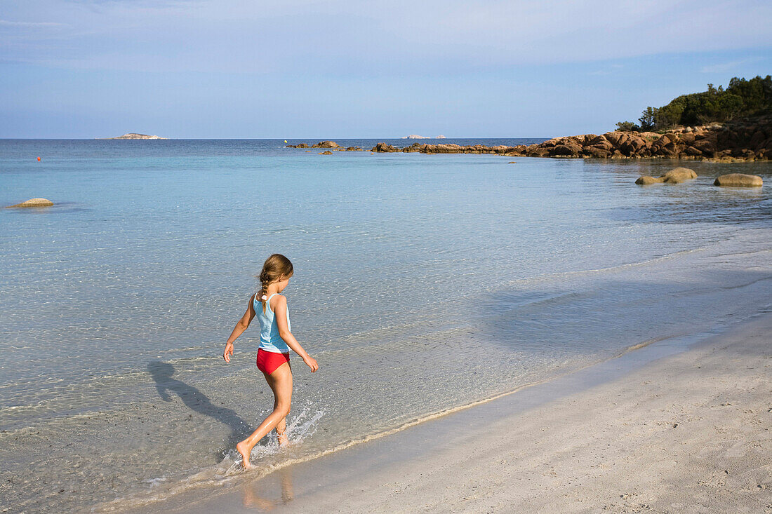Girl walking along sandy beach, Palombaggia, Corsica, France