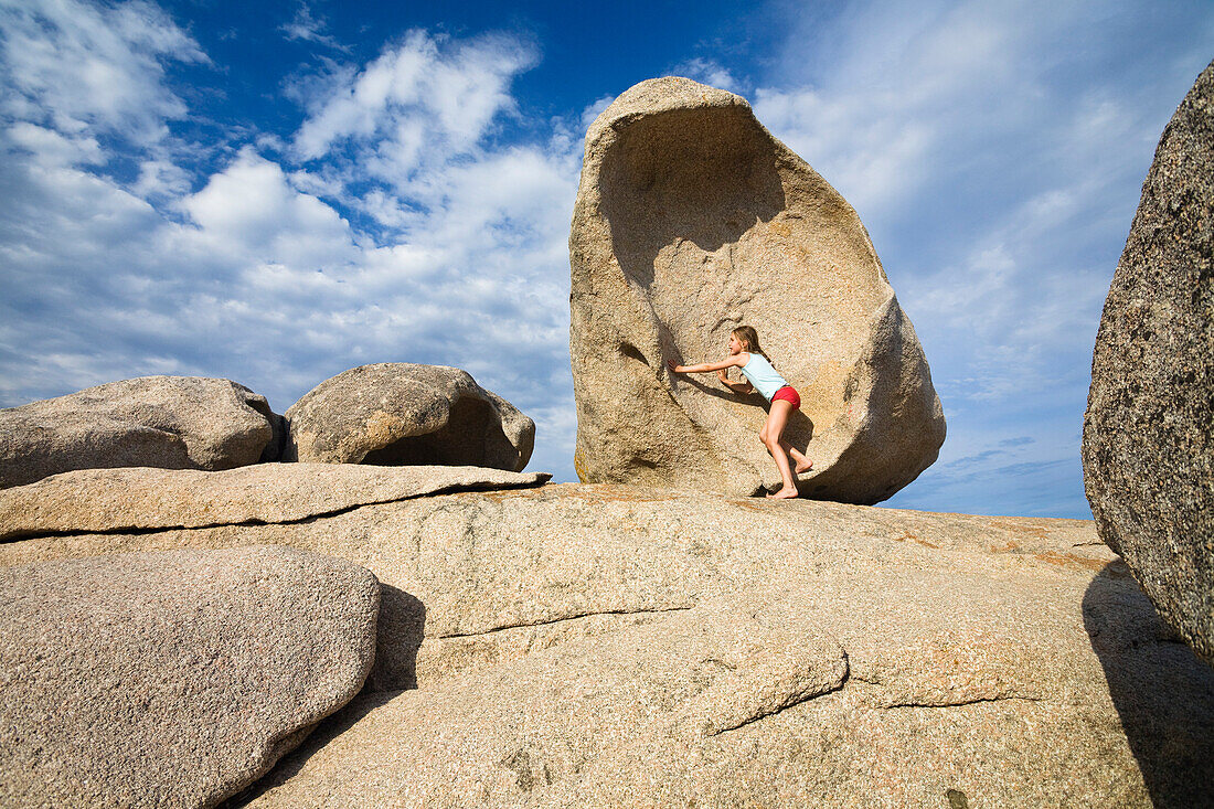 Mädchen klettert auf den Felsen am Strand von Palombaggia, Südostküste, Korsika, Frankreich, Europa