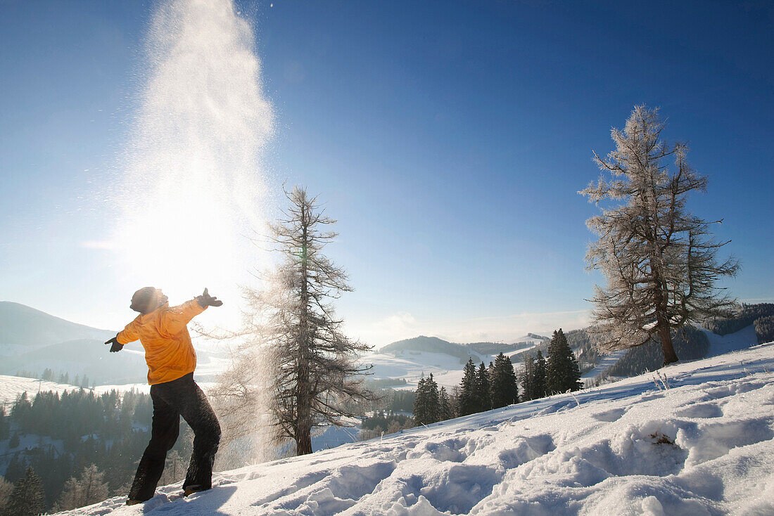Mann wirft Schnee hoch, Steiermark, Österreich