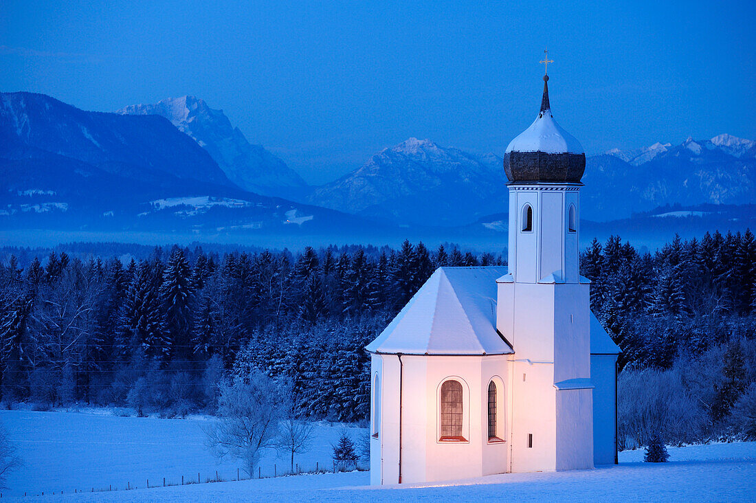 Verschneite Kirche vor Zugspitze und Ammergauer Alpen am Abend, Penzberg, Werdenfelser Land, Oberbayern, Bayern, Deutschland, Europa
