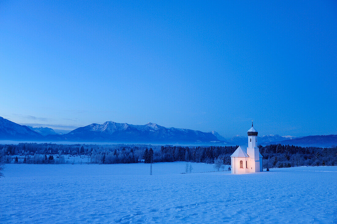 Snow covered church in front of range of Alps in the evening, Penzberg, Werdenfelser Land, Upper Bavaria, Bavaria, Germany, Europe