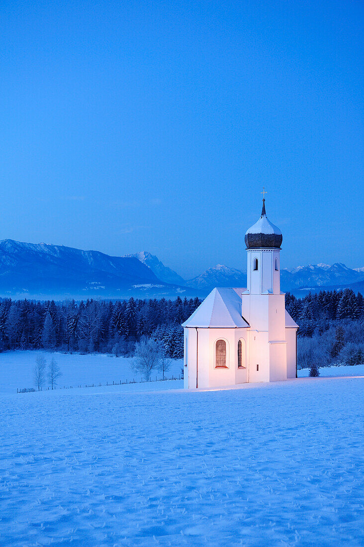 Verschneite Kirche vor Zugspitze und Ammergauer Alpen am Abend, Penzberg, Werdenfelser Land, Oberbayern, Bayern, Deutschland, Europa