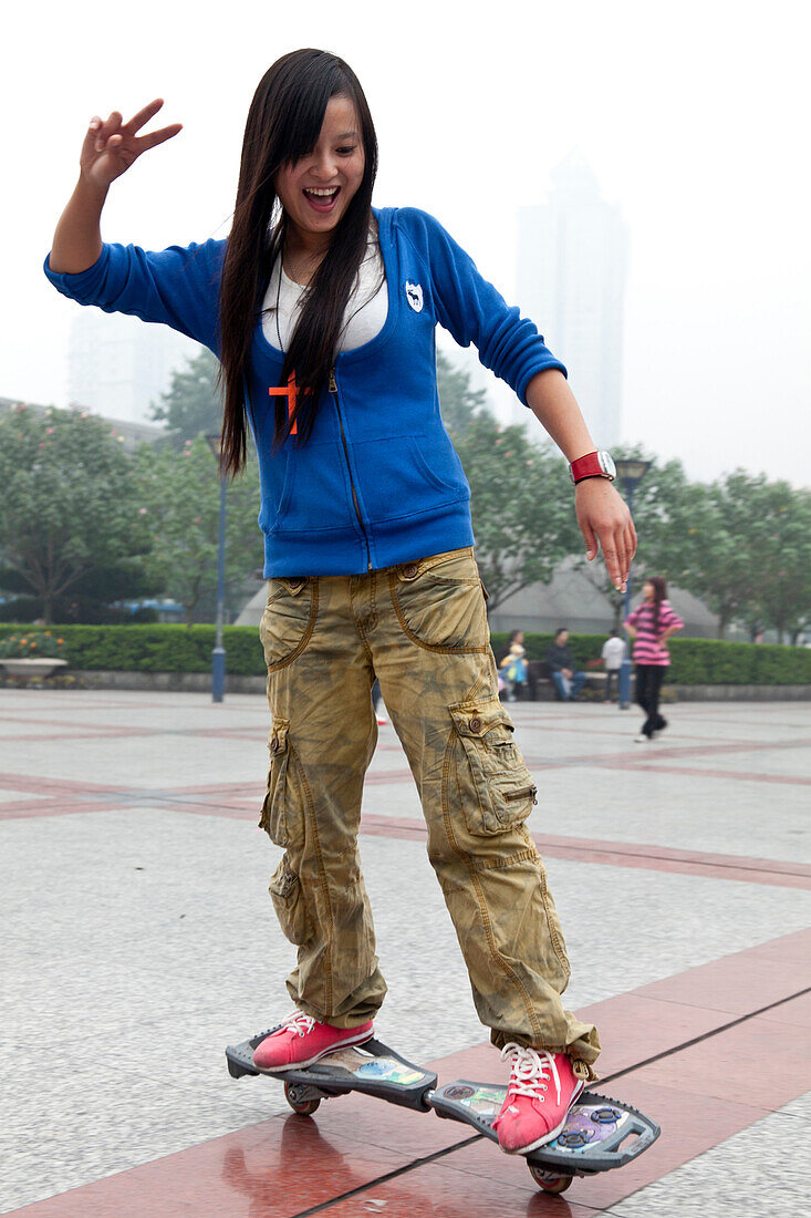 Chinesisches Mädchen fährt mit besonderem Skateboard, Freizeitgestaltung auf dem Platz vor dem Walmart Einkaufszentrum, Stadtteil Shapingba von Chongqing, Hochhäuser, Chongqing, VR China