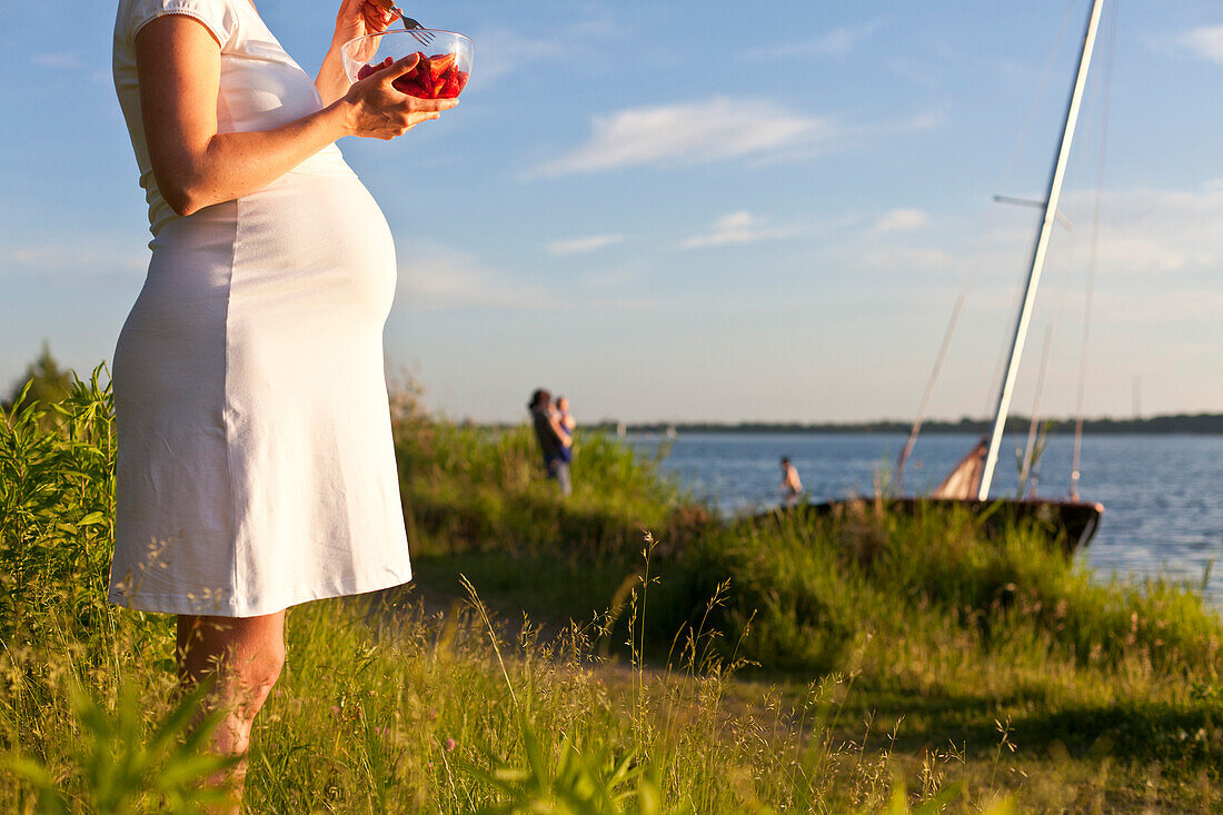 Schwangere Frau isst Erdbeeren am Cospudener See, Leipzig, Sachsen, Deutschland