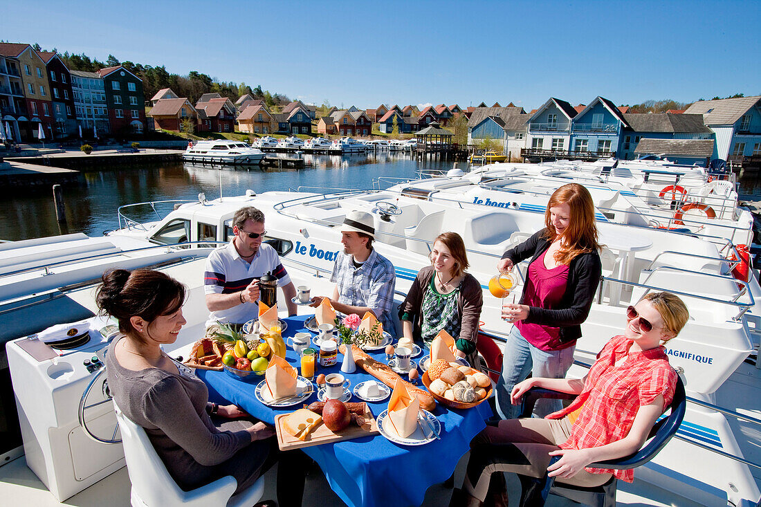 Friends enjoying breakfast on board a houseboat at the Wolfsbusch marina, Kleinzerlang, near Rheinsberg, North Brandenburg Lake District, Brandenburg, Germany