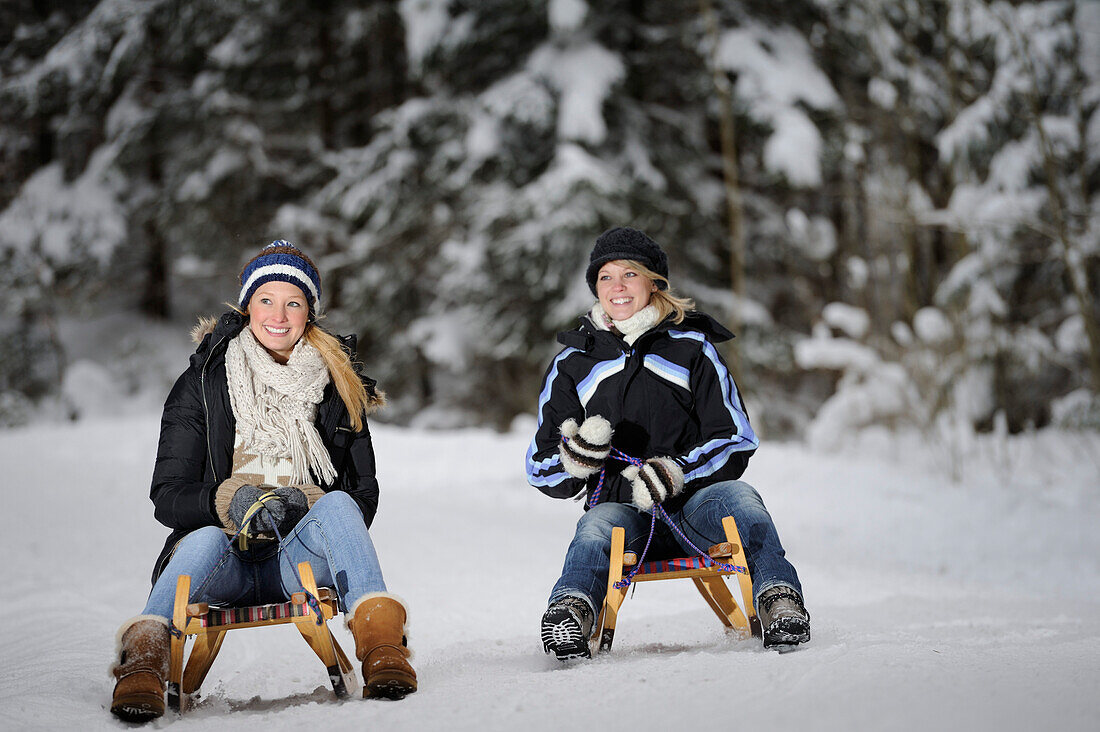 Two young women on a sleigh ride, valley of Leitzachtal, Upper Bavaria, Bavaria, Germany, Europe