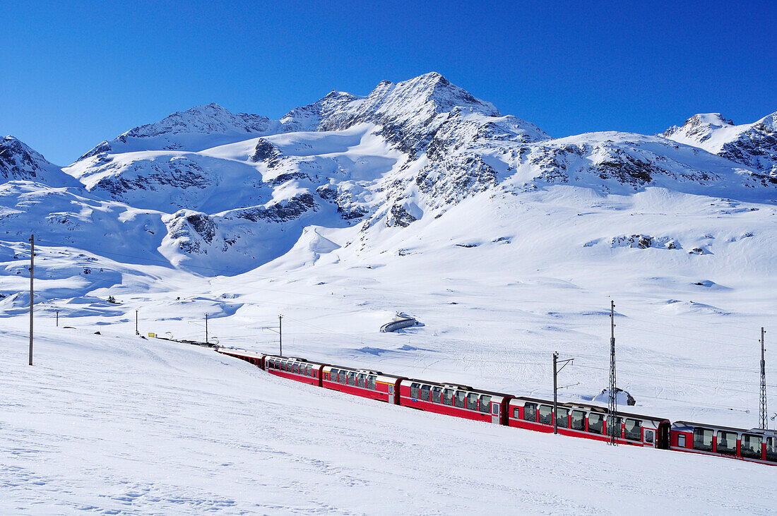 Zug der Rhätische Bahn fährt durch Winterlandschaft zum Berninapass, UNESCO Weltkulturerbe Rhätische Bahn, Rhätische Bahn, Albula-Bernina-Linie, Berninabahn, Berninagruppe, Oberengadin, Engadin, Graubünden, Schweiz, Europa