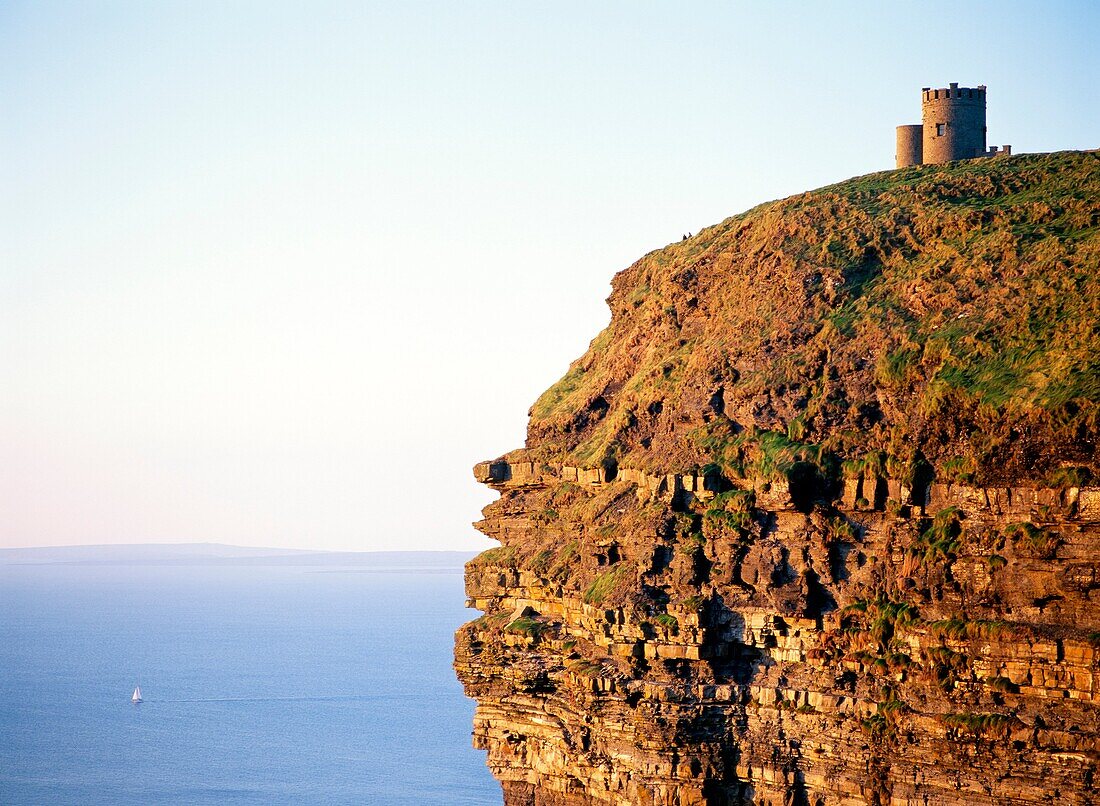 O’Briens Tower on top of the sheer Cliffs of Moher, County Clare, west Ireland Sailboat yacht in distance Atlantic Ocean