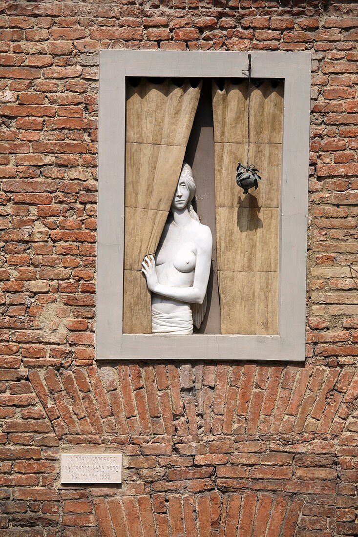 Artwork of a naked woman at window in the Bruco district Siena historic center, Siena, Italy