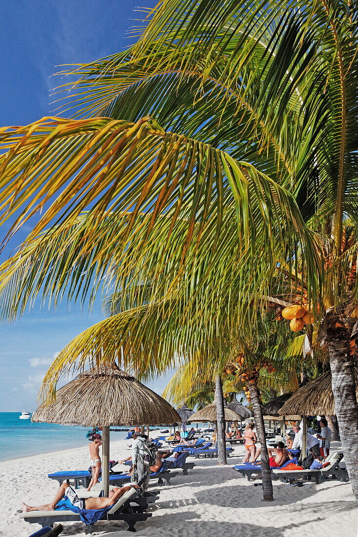 Palmen und Menschen am Strand des Beachcomber Hotel Paradis &amp,amp; Golf Club, Mauritius, Afrika