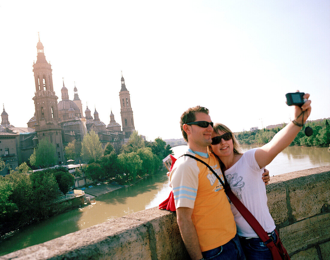 Couple taking photographs of themselves on Puente de Piedra, Saragossa, Aragon, Spain
