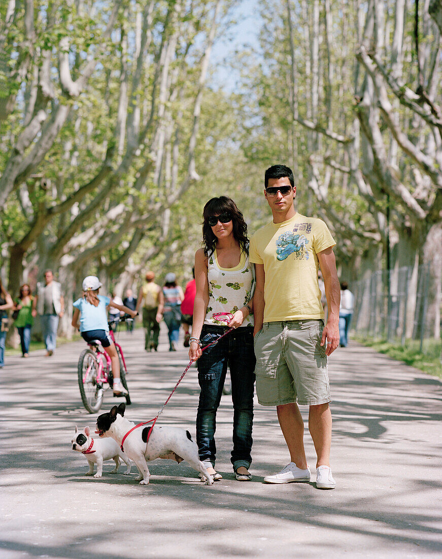 Couple walking their dogs, sycamore tree lined path through Parque Primo de Rivera, Saragossa, Aragon, Spain