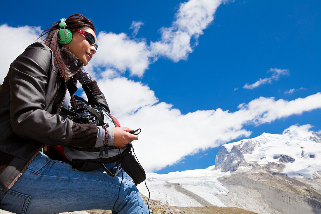 Junge Frau mit Kopfhörer, Klimahörpfad von myclimate, Monte Rosa im Hintergrund, Zermatt, Walliser Alpen, Kanton Wallis, Schweiz