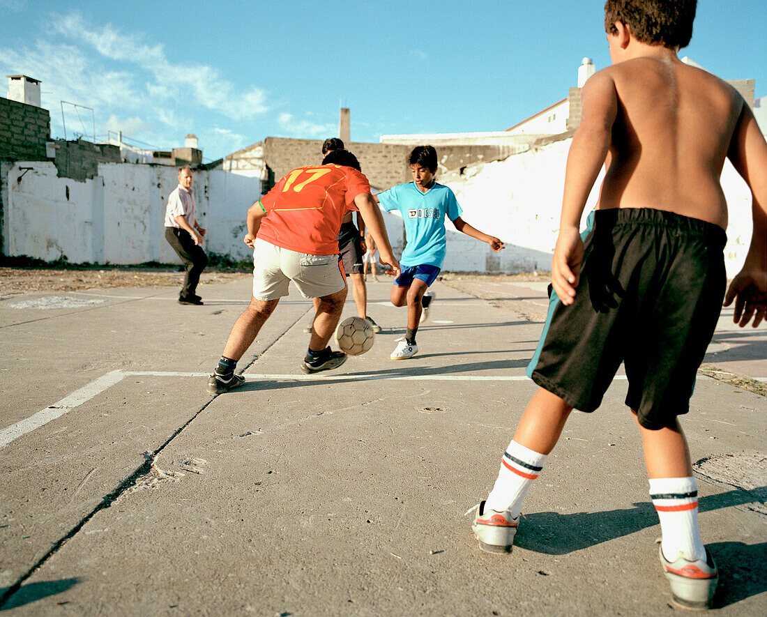 Kids playing football between ragged houses, harbour of Ponta Delgada, southern coast of Sao Miguel island, Azores, Portugal