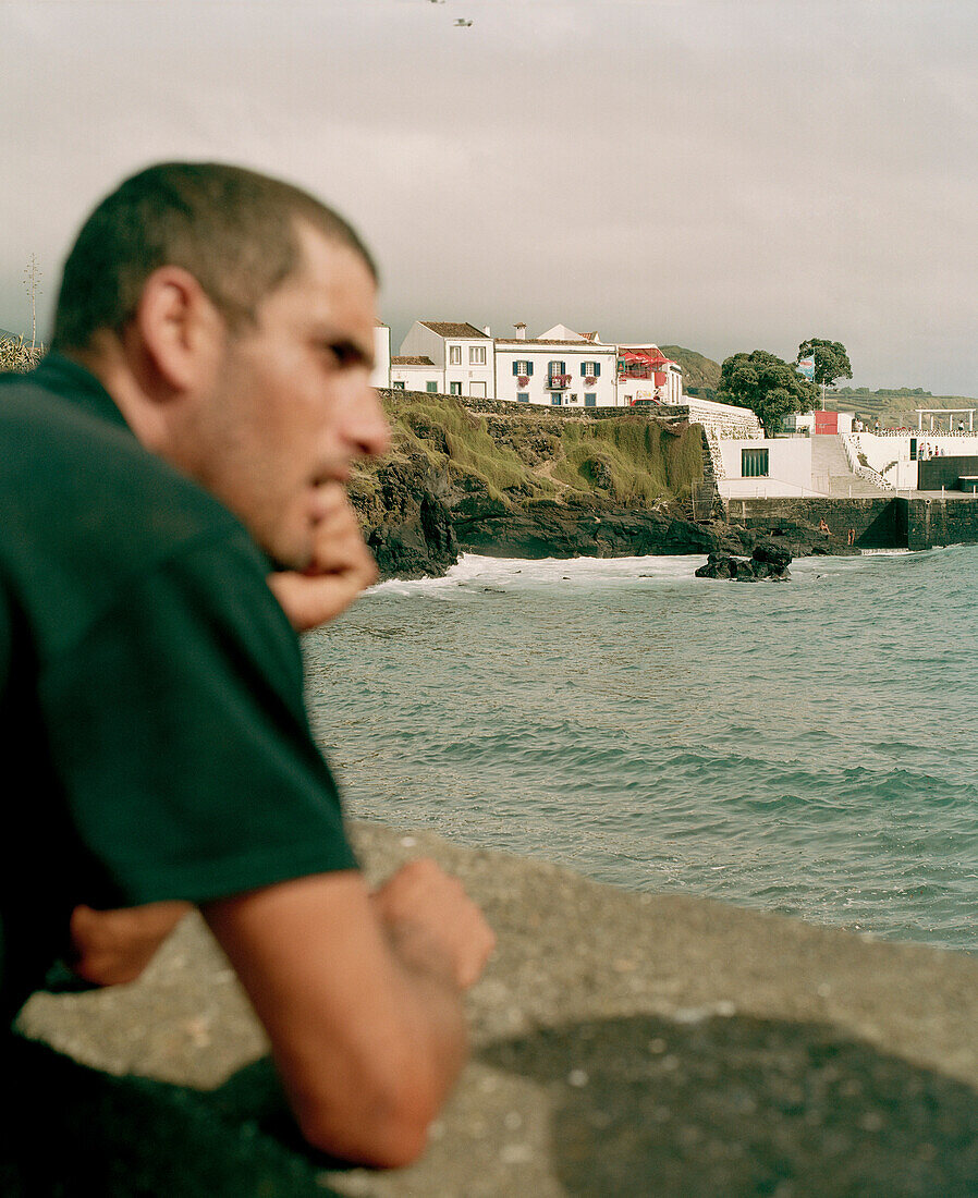 Mann blickt aufs Meer, Hafenbucht von Lagoa, Südküste der Insel Sao Miguel, Azoren, Portugal
