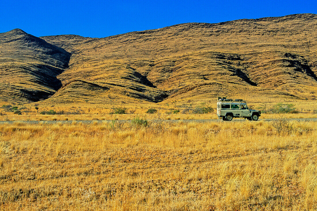 Land Rover on arid grassland road, Namibia