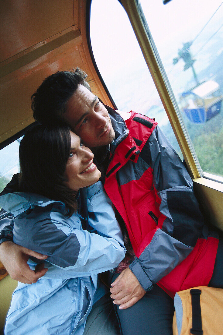 Mid adult couple looking out of a cabin of an overhead cable car, Upper Bavaria, Germany