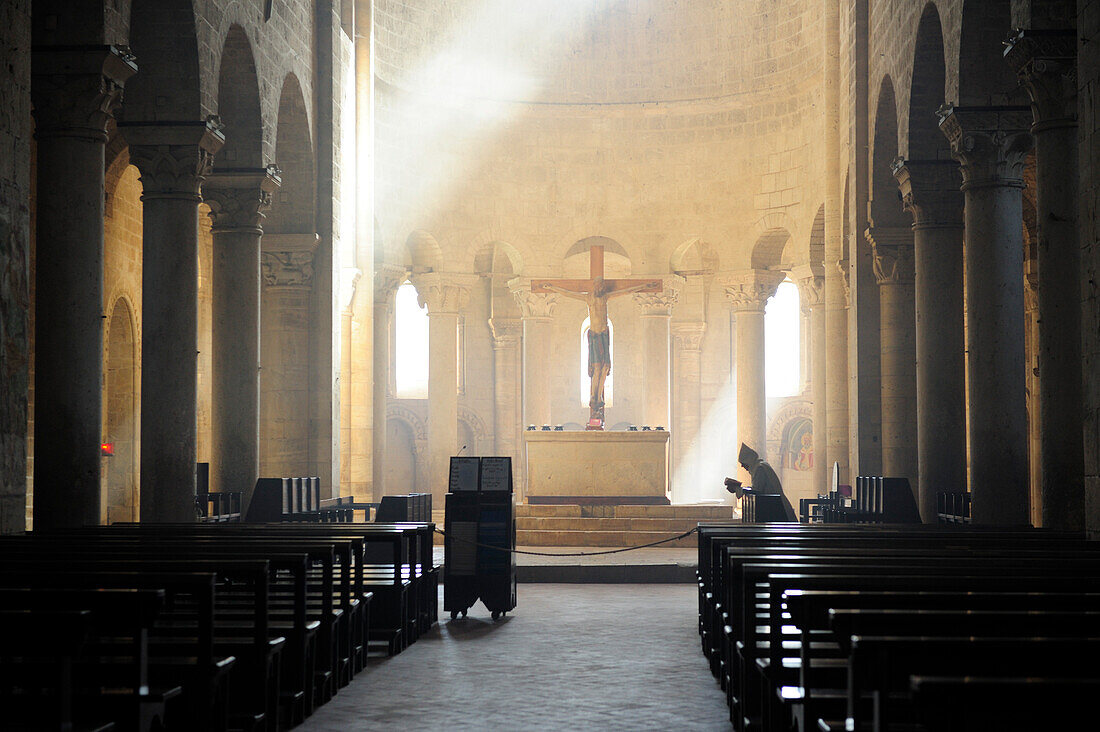 Mönch betet vor Altar in romanischer Kirche San Antimo, San Antimo, Toskana, Italien