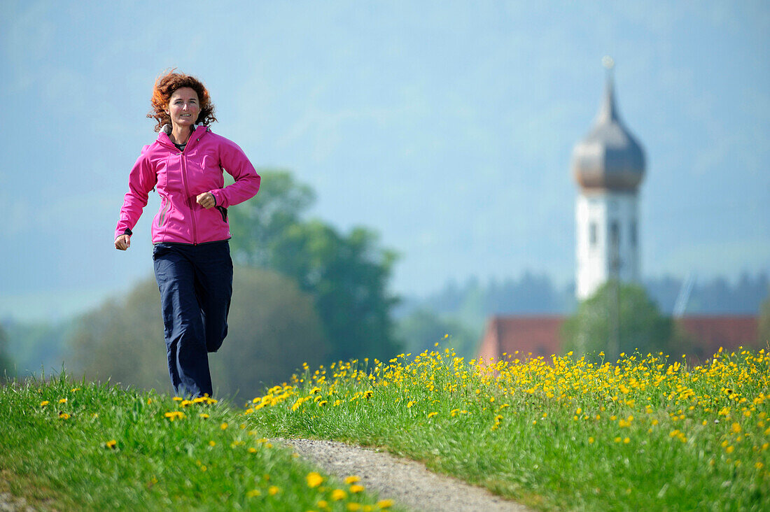 Frau läuft auf einem Weg durch eine Blumenwiese, Oberbayern, Bayern, Deutschland