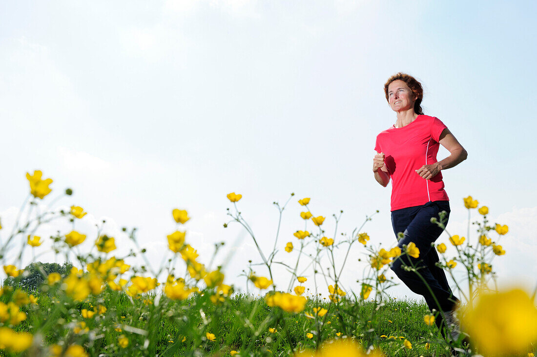 Woman jogging through a meadow, Upper Bavaria, Bavaria, Germany