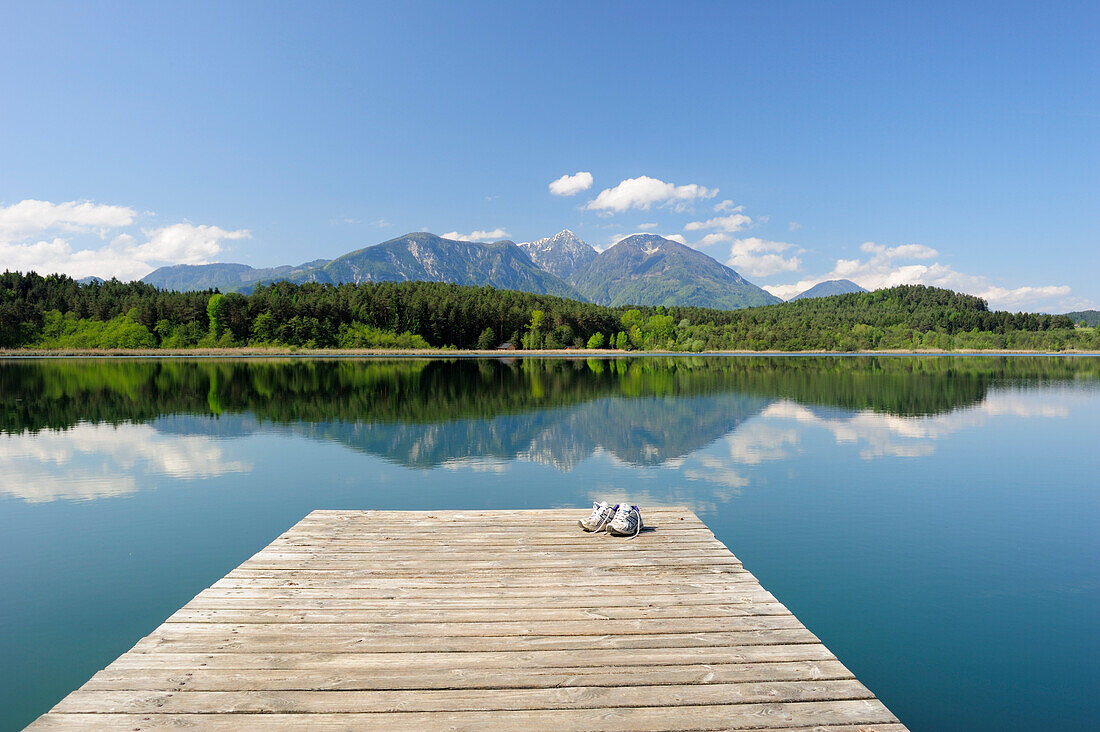 Ein Paar Schuhe steht auf Holzsteg im Turnersee, Karawanken im Hintergrund, Turnersee, Kärnten, Österreich, Europa