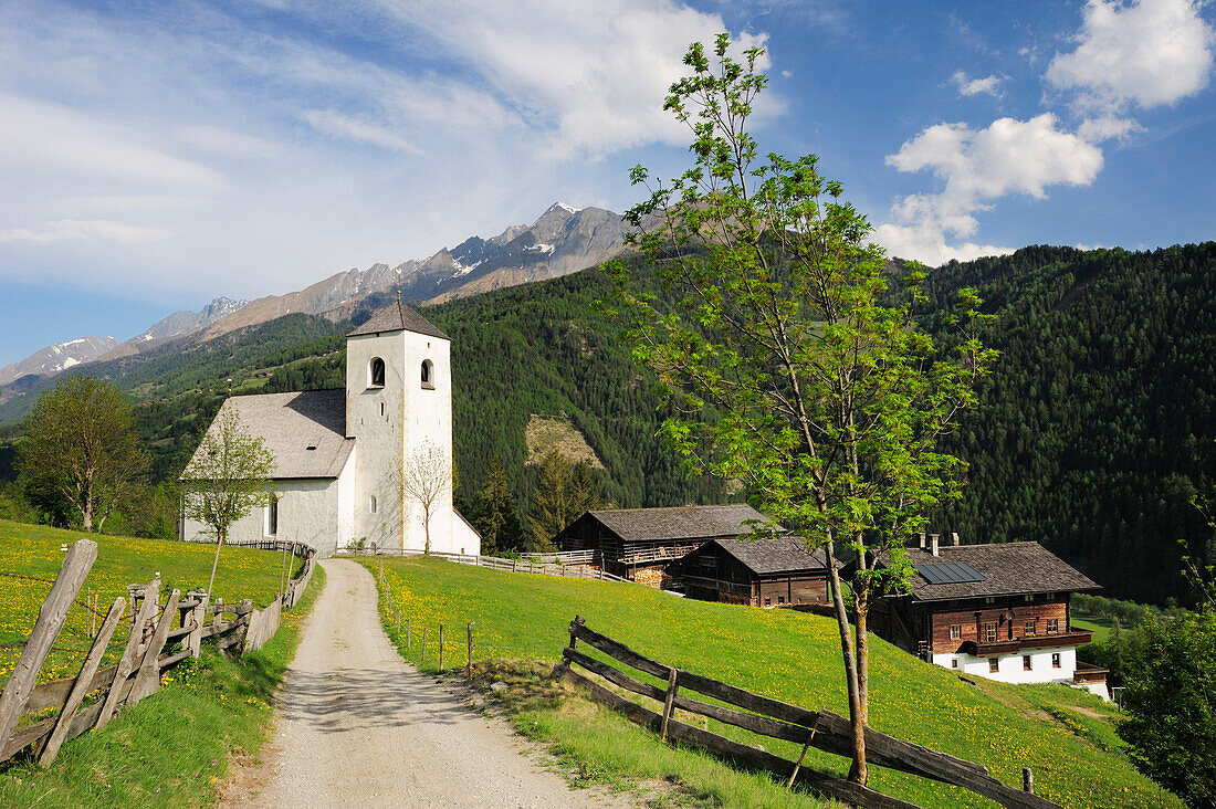 Track leading towards romanesque church St Nicholas, farmhouses in the background, Matrei, East Tyrol, Austria, Europe