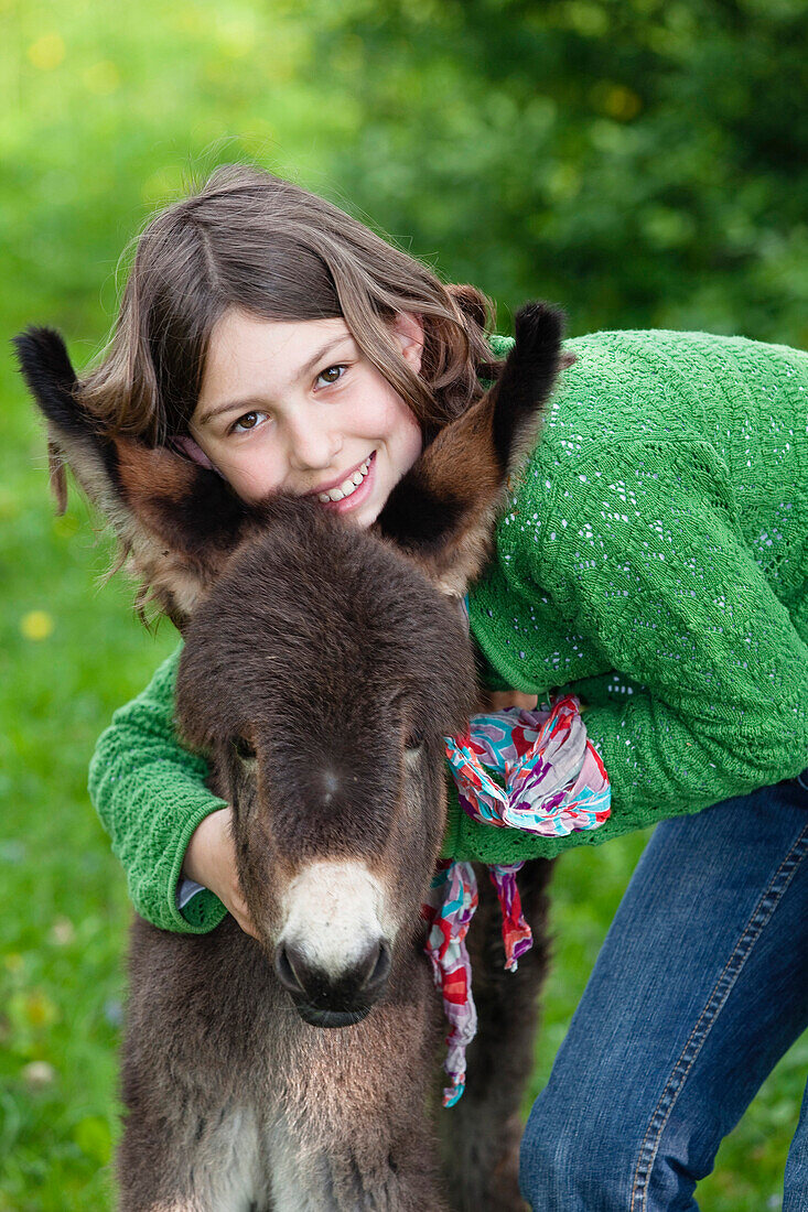 Girl 11 years, with donkey foal, Bavaria, Germany