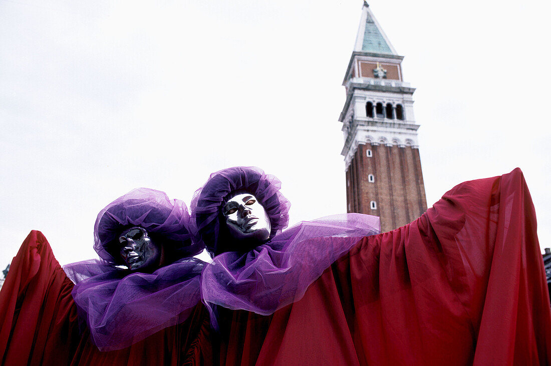 Carnival masks in St Mark's Square with campanile tower, Venice, Italy