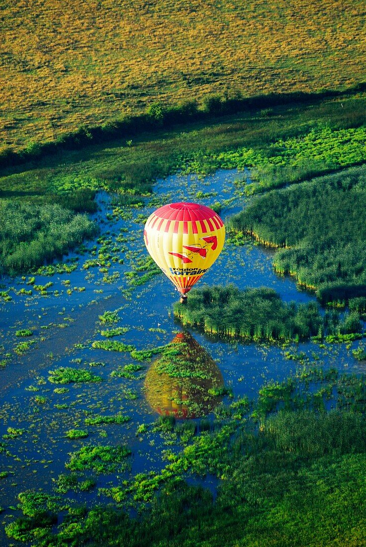 Hot air balloon ofLorraine region,  flying over Lachaussee lake surface. Meuse, Lorraine region, France