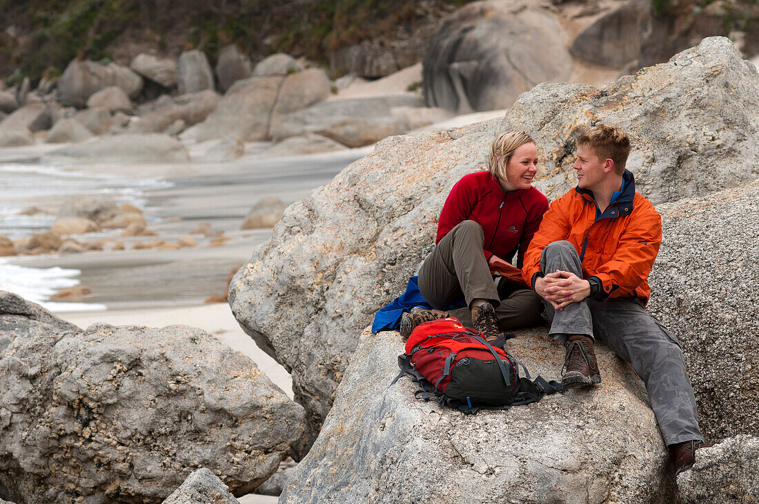 Couple having a rest on rocks at Little Oberon Bay, Wilsons Promontory National Park, Victoria, Australia