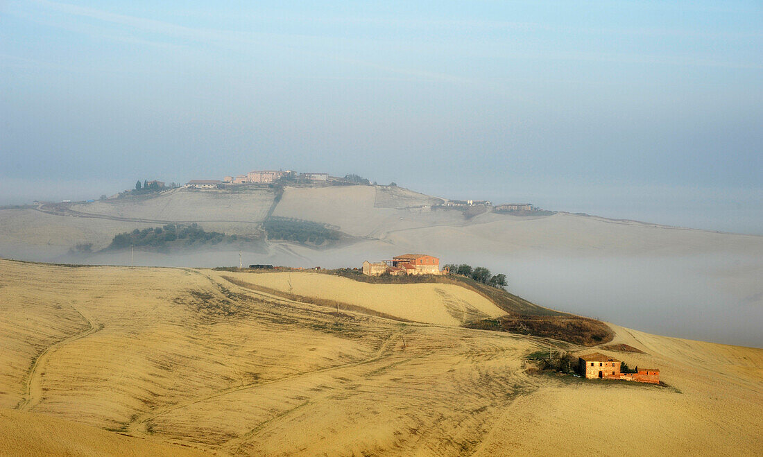 View of homesteads on hills in the fog, Crete, Tuscany, Italy, Europe