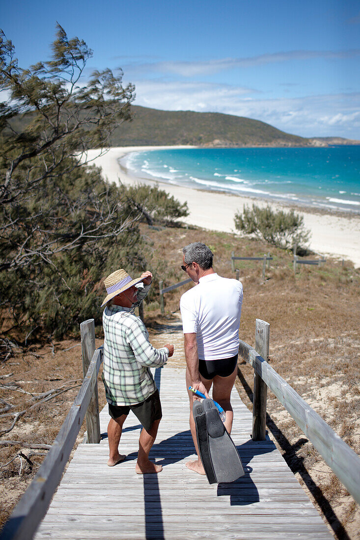 Geoff Mercer, Hotelier und Bewohner von Great Keppel Island, mit Tourist auf dem Weg zum Strand,  Great Keppel island, Great Barrier Reef Marine Park, UNESCO Weltnaturerbe, Queensland, Australien