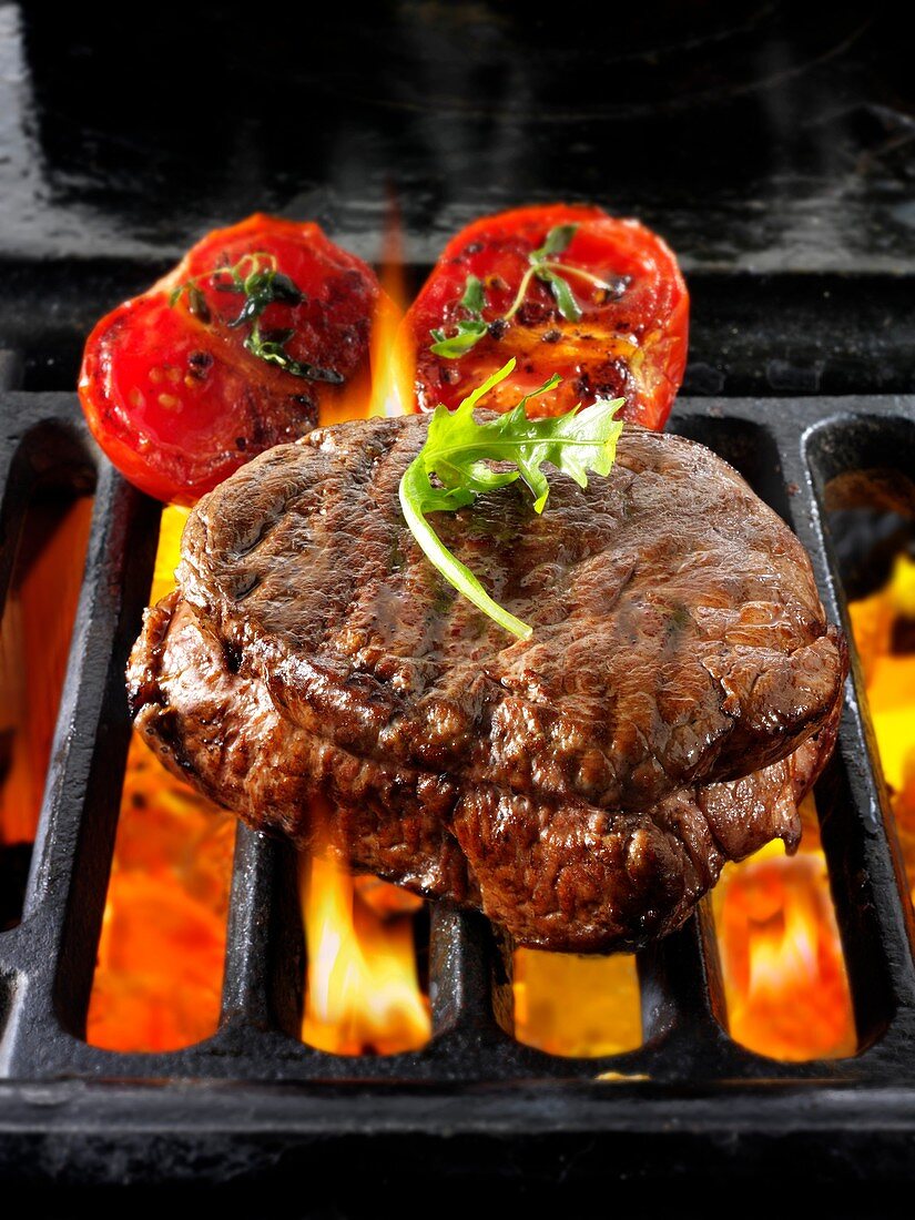 Beef fillet steaks & tomatoes being cooked on a bbq.