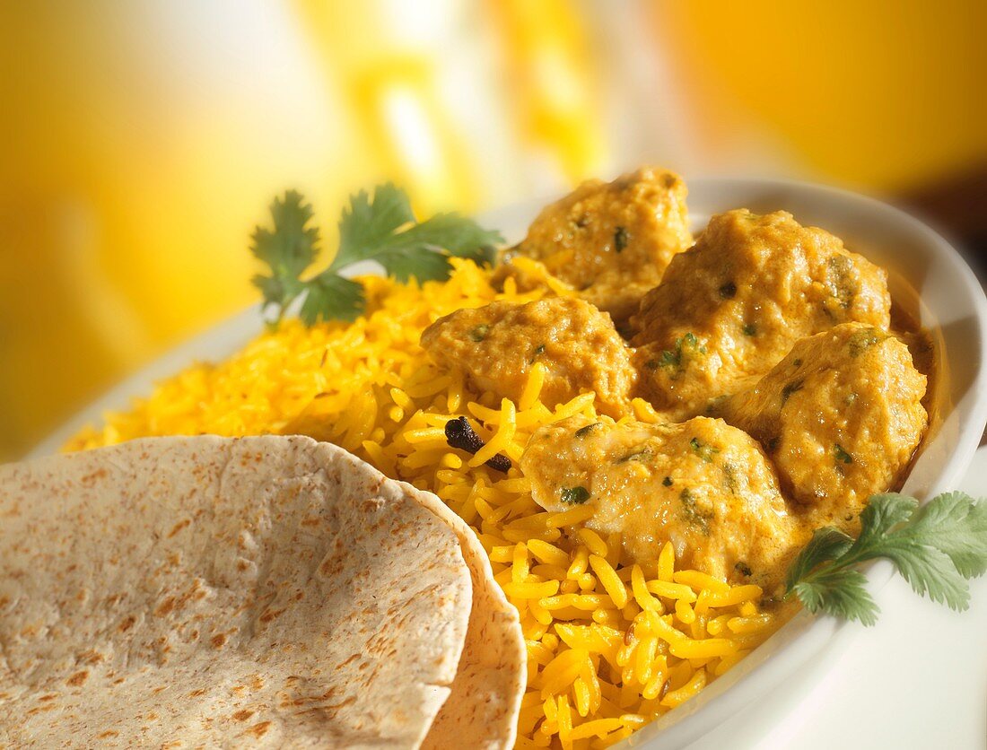 Chicken Korma, pilau rice, naan bread in a white dish yellow background