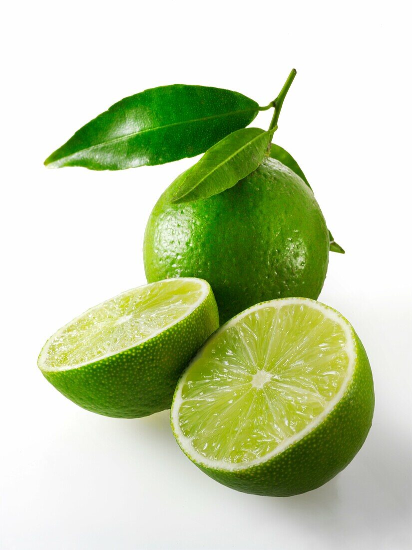 Fresh whole and cut lime fruit with leaves