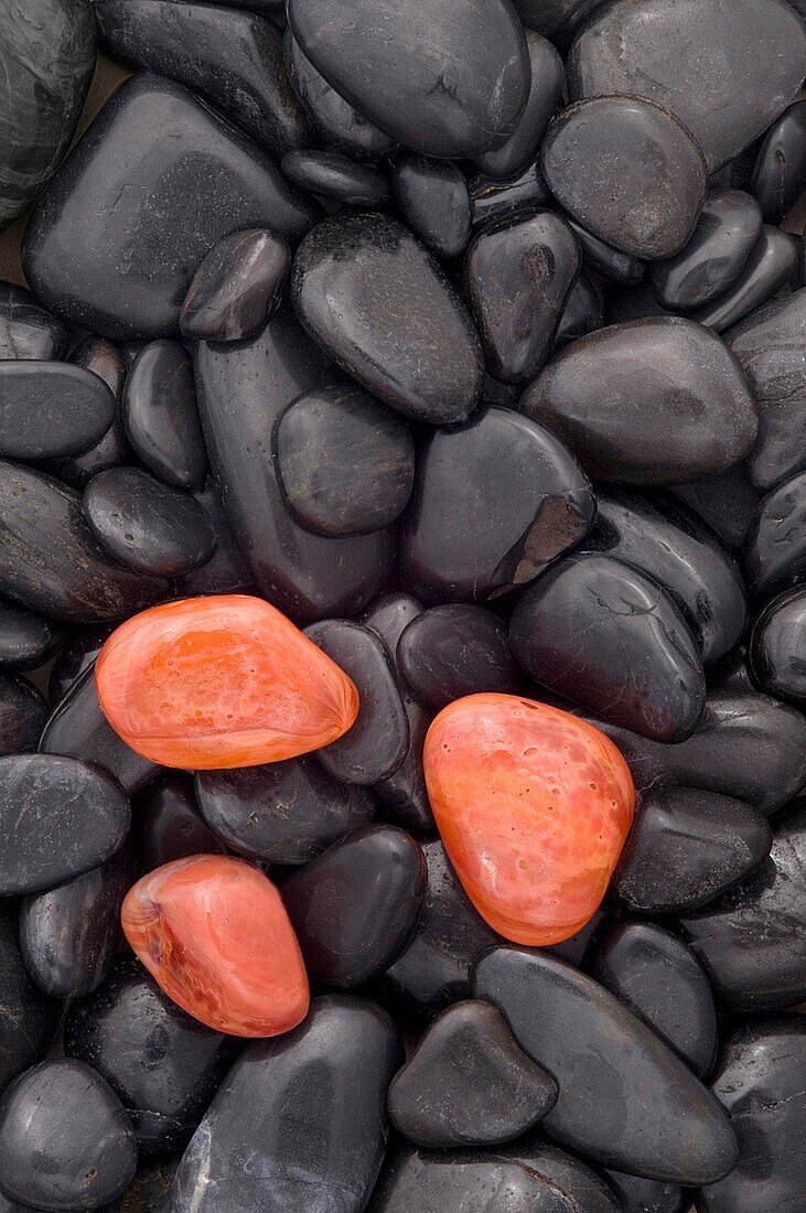 Three glowing orange red pebbles on a background of black pebbles