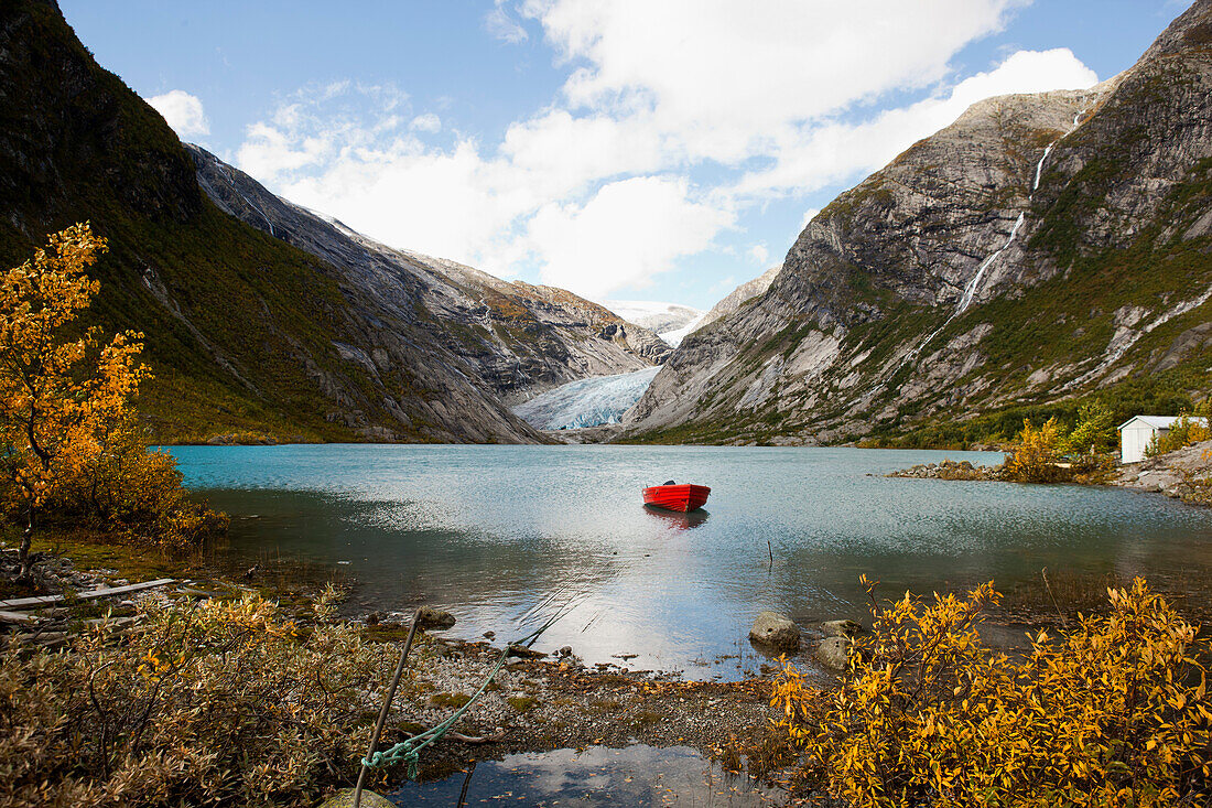 Blick auf Nigardsbreen, rotes Holzboot liegt im See vor der Gletscherzunge, Herbst, Jostedalen, Nigardsbreen, Jostedalsbreen Nationalpark, Sogn og Fjordane, Norwegen, Skandinavien, Europa