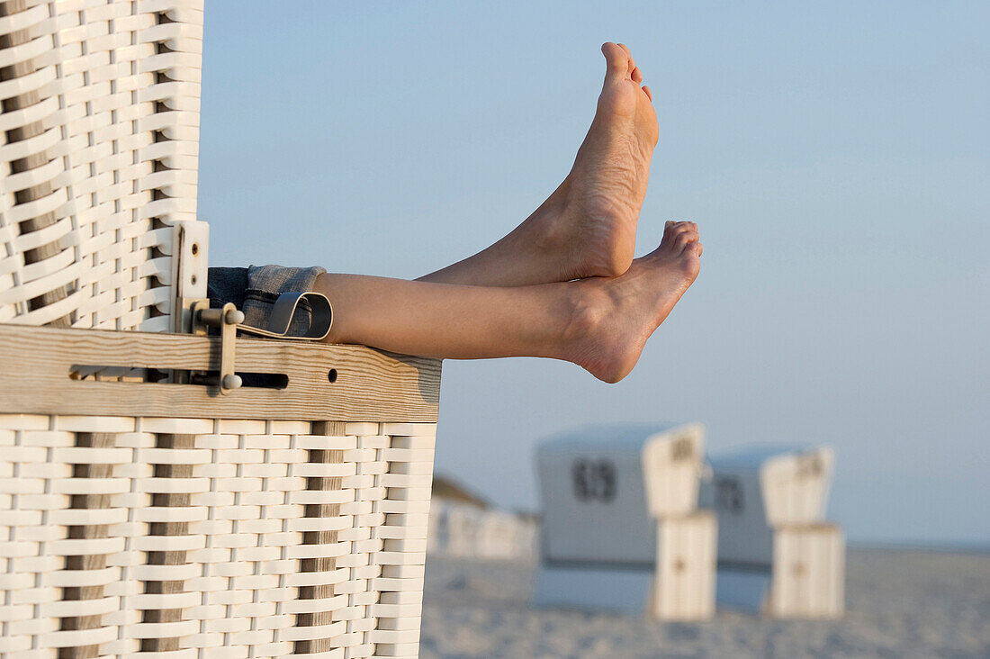 Woman relaxing in roofed wicker beach chair, Westerland, Sylt, Schleswig-Holstein, Germany