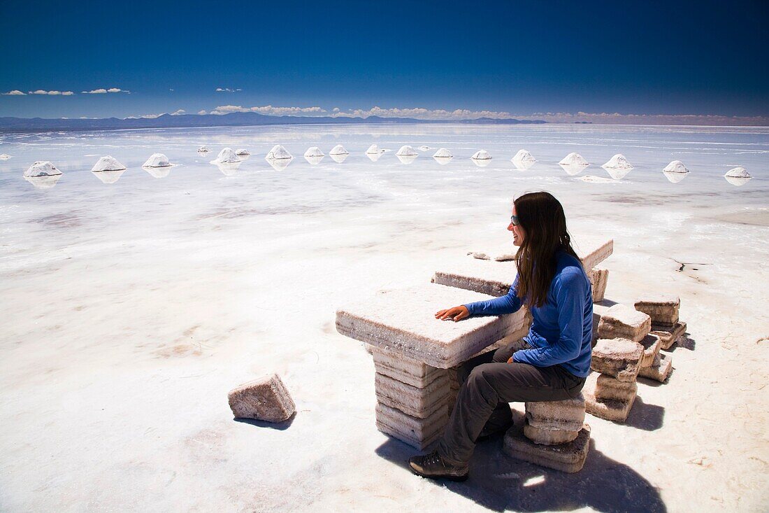 Bolivia, Southern Altiplano, Salar de Uyuni Tourist resting on a seat constructed of salt, located on the Salar de Uyuni salt flat