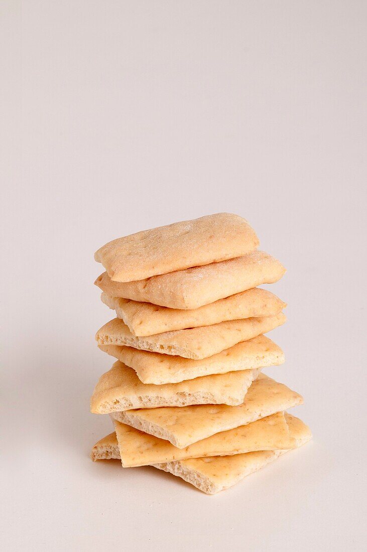 Close-up of organic wheat crackers stacked high on top of each other on a white background