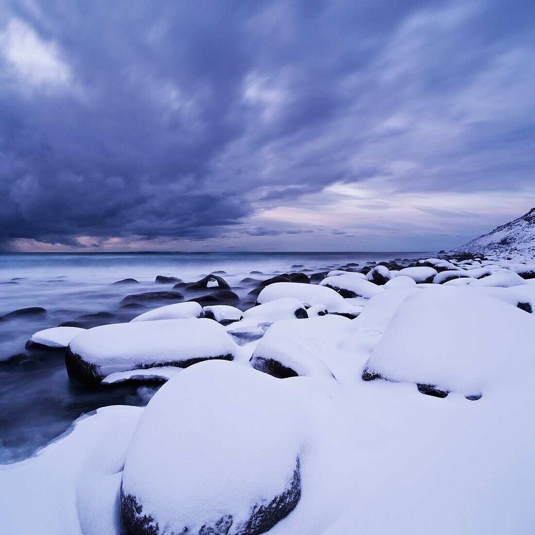 Snow covered rocks at Unstad beach, Vestvågøy, Lofoten islands, Norway