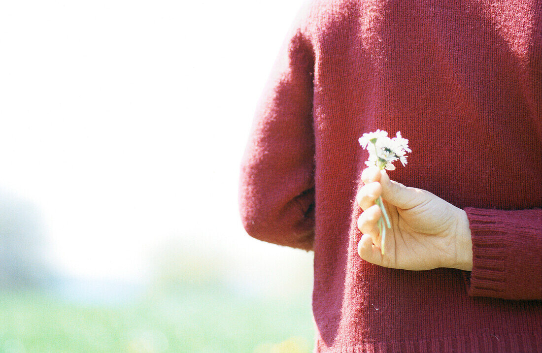 Child holding flowers behind back