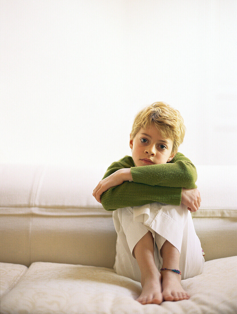 Girl sitting on sofa with knees up and arms folded