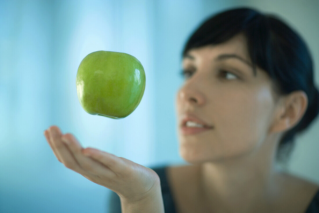 Apple floating in air above woman's hand