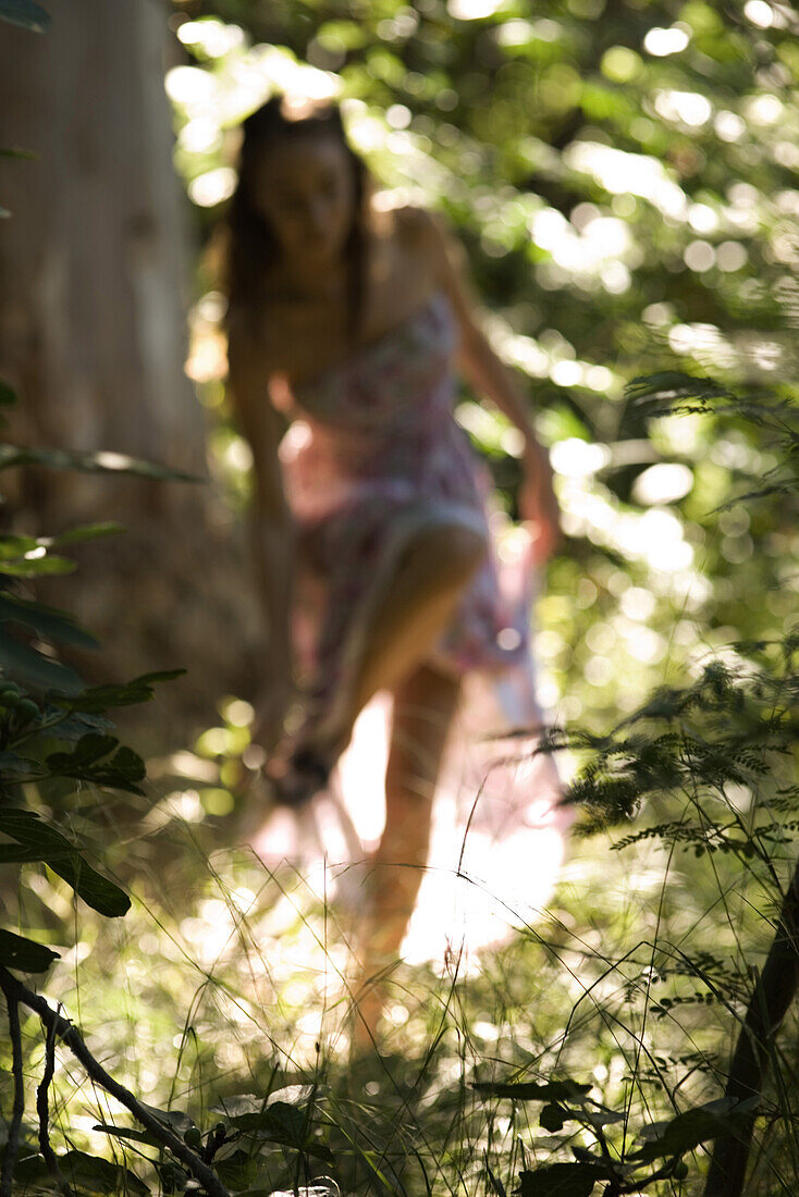 Woman standing on one leg in forest, touching her foot, defocused