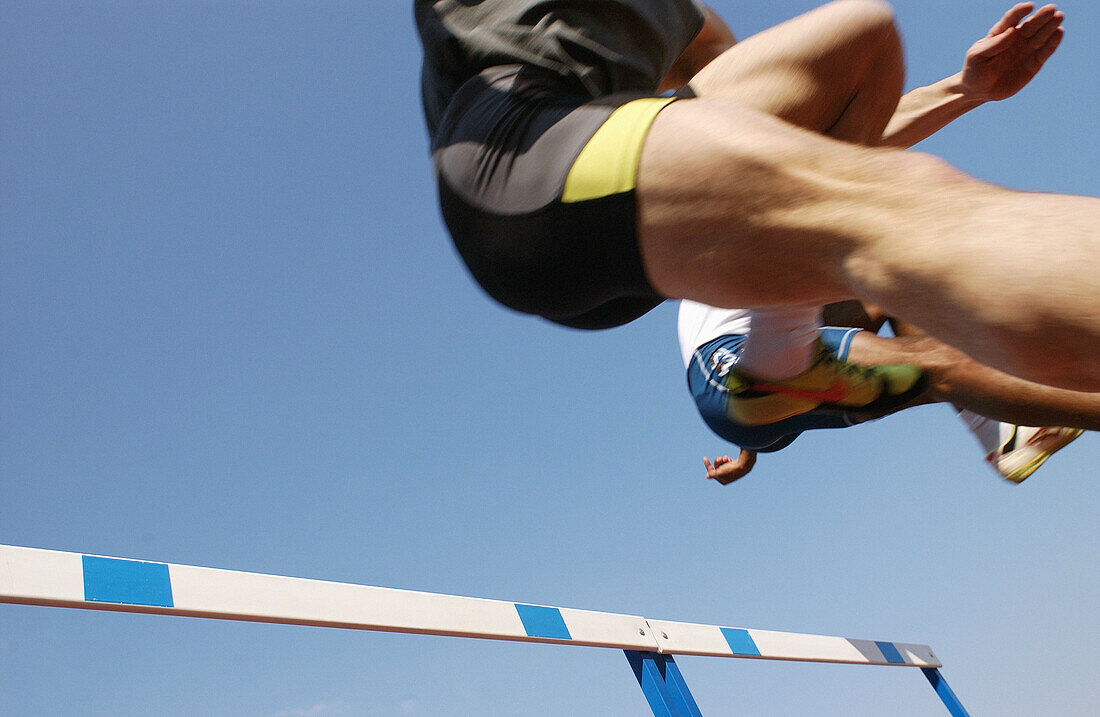 Athlete jumping hurdle, low angle view