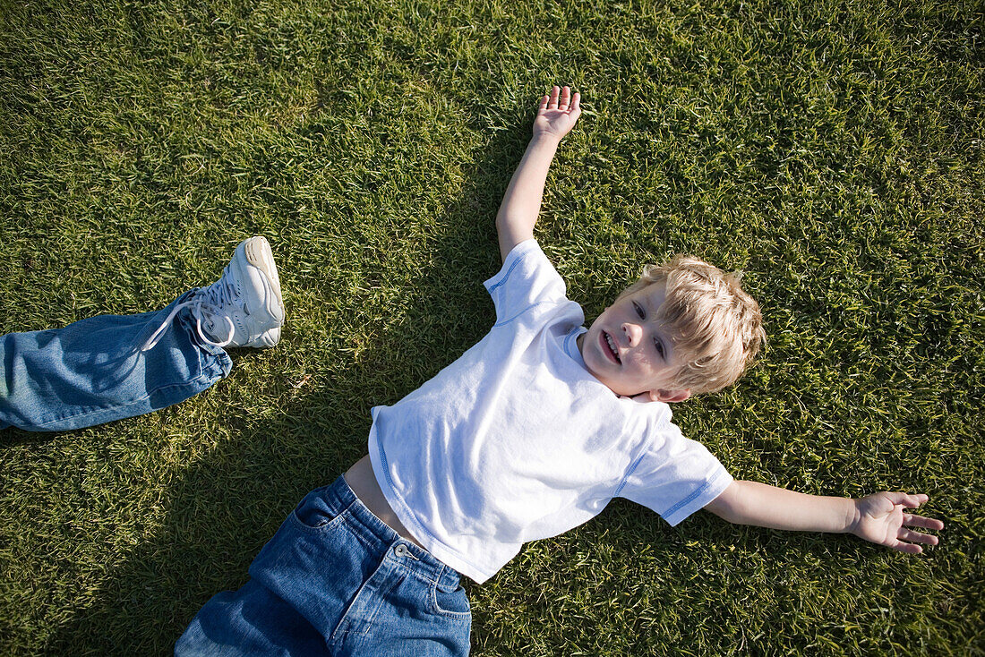 Boy lying on grass, high angle view