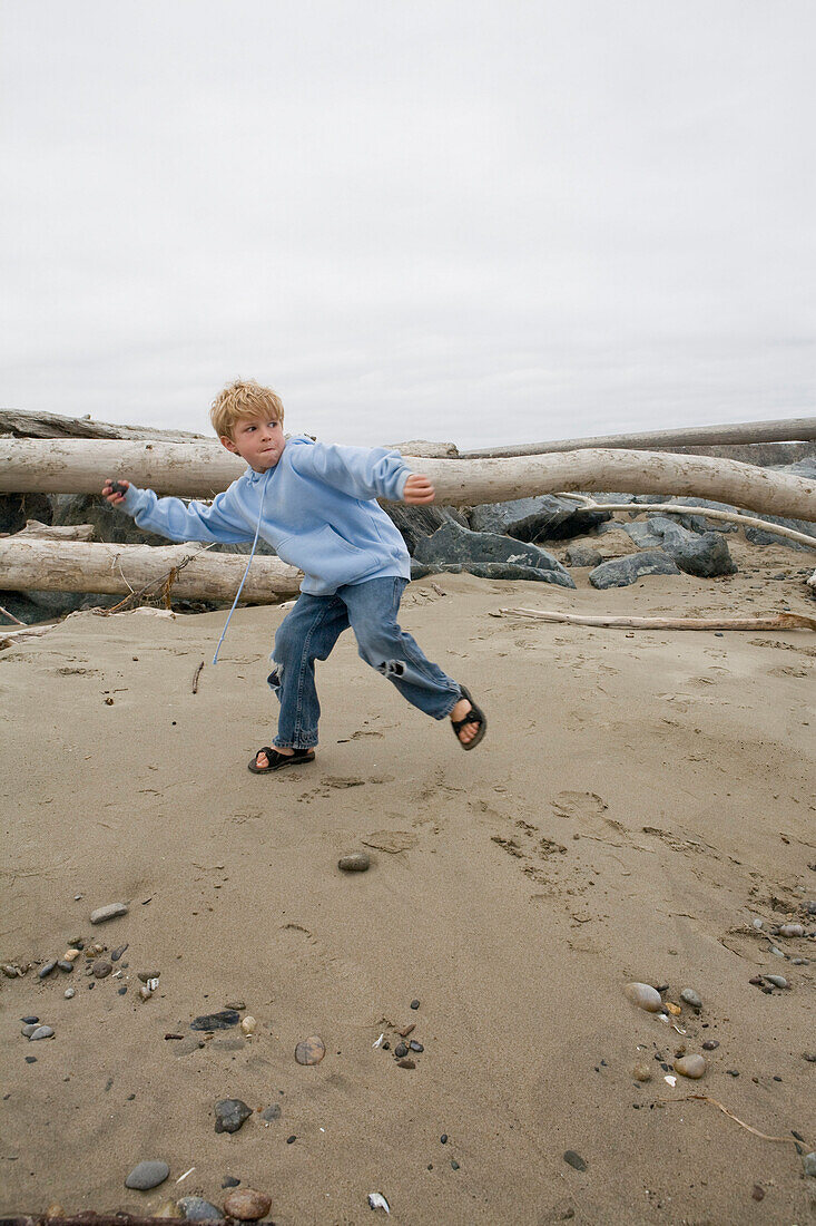 Young Boy Throwing Rocks on Beach, Oregon, USA