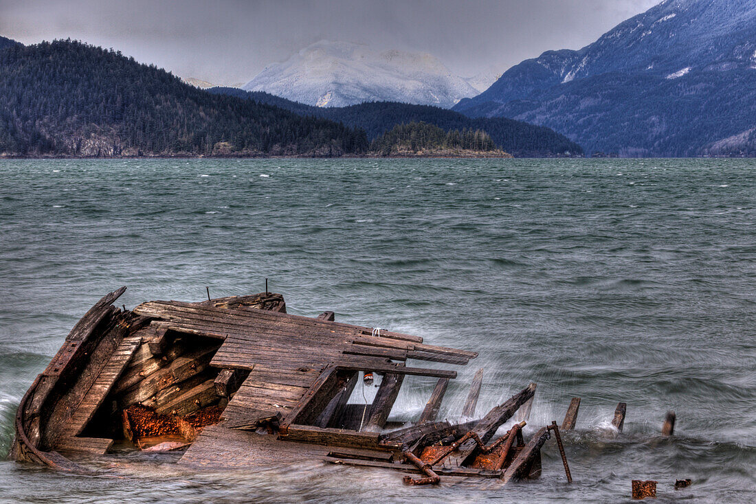 Shipwreck in Blustery Waters with Mountains in Background, British Columbia, Canada